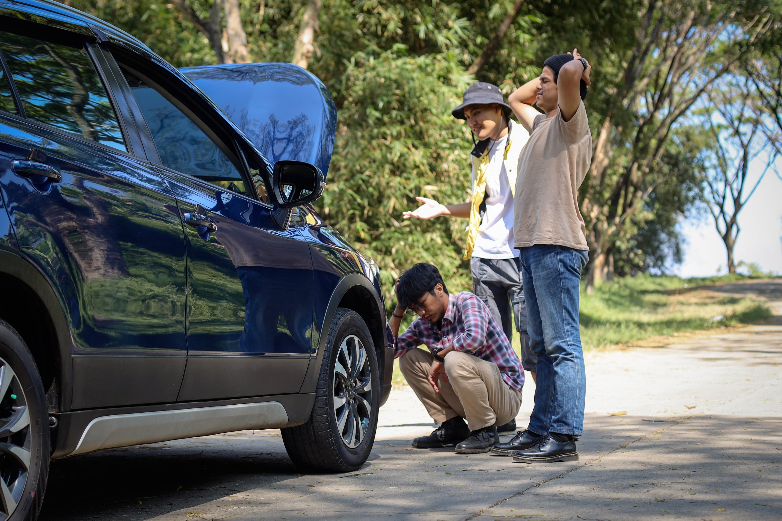 Two men stand by a blue SUV on a road.