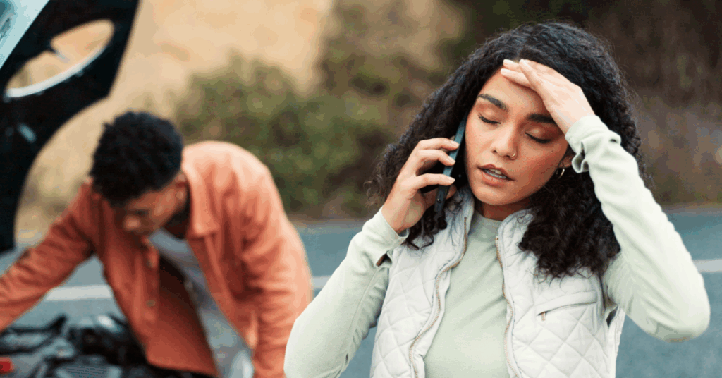 A woman with curly hair talks on a phone outdoors.