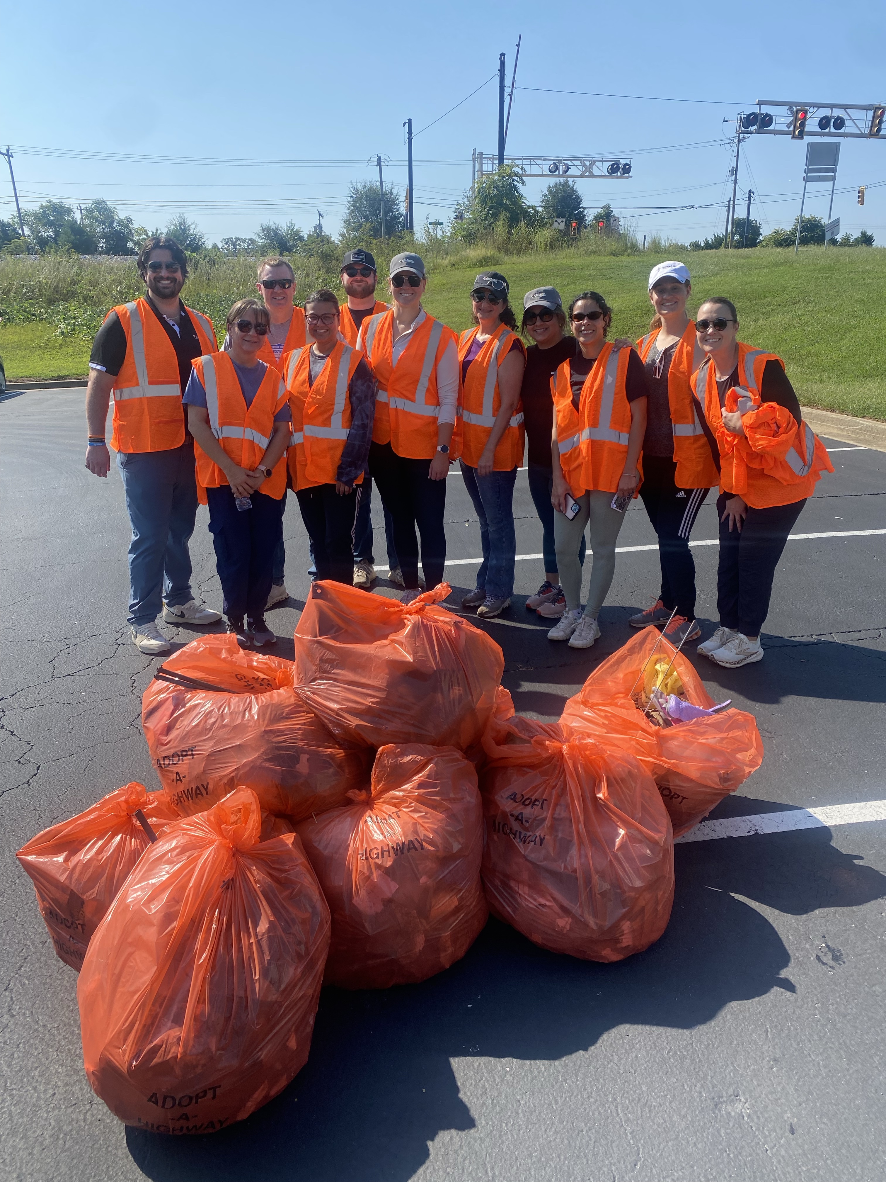 People stand behind large orange bags on a road.