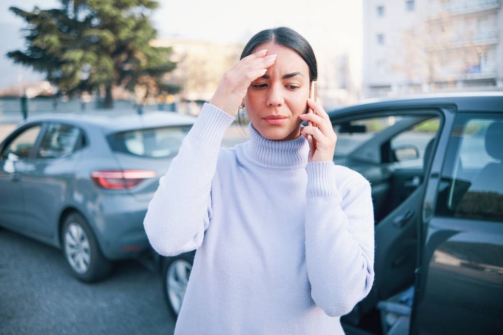 Photo of a girl with phone in hand next to cars