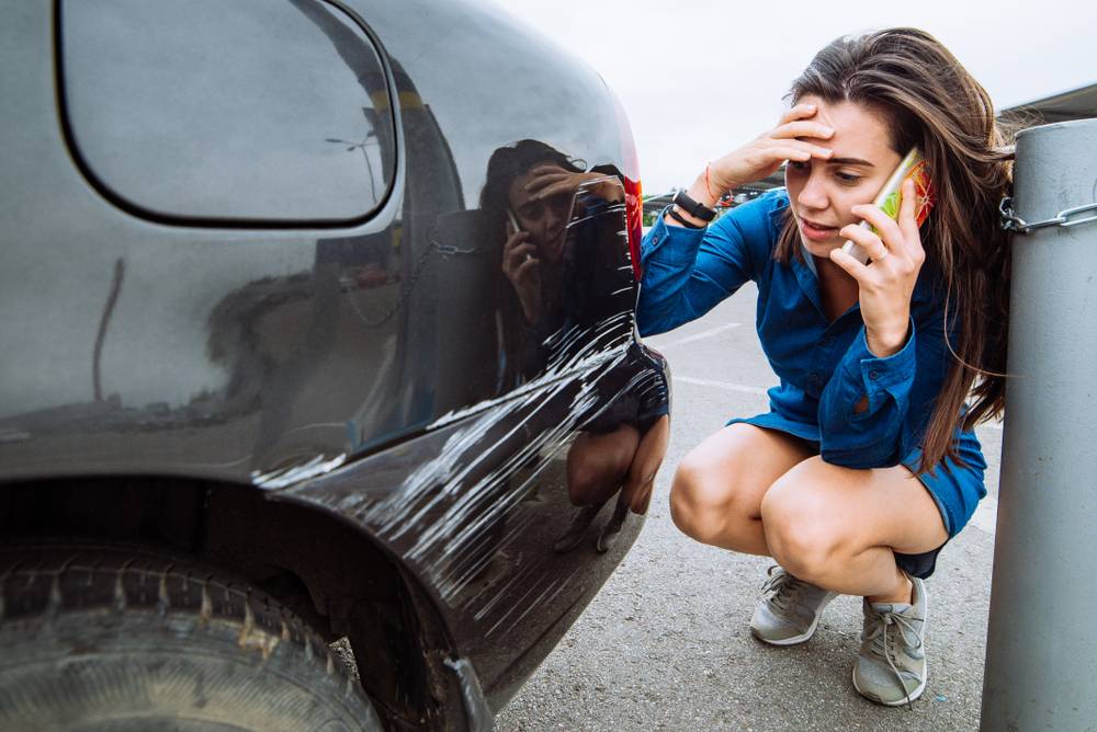 Photo of girl next to scratched car