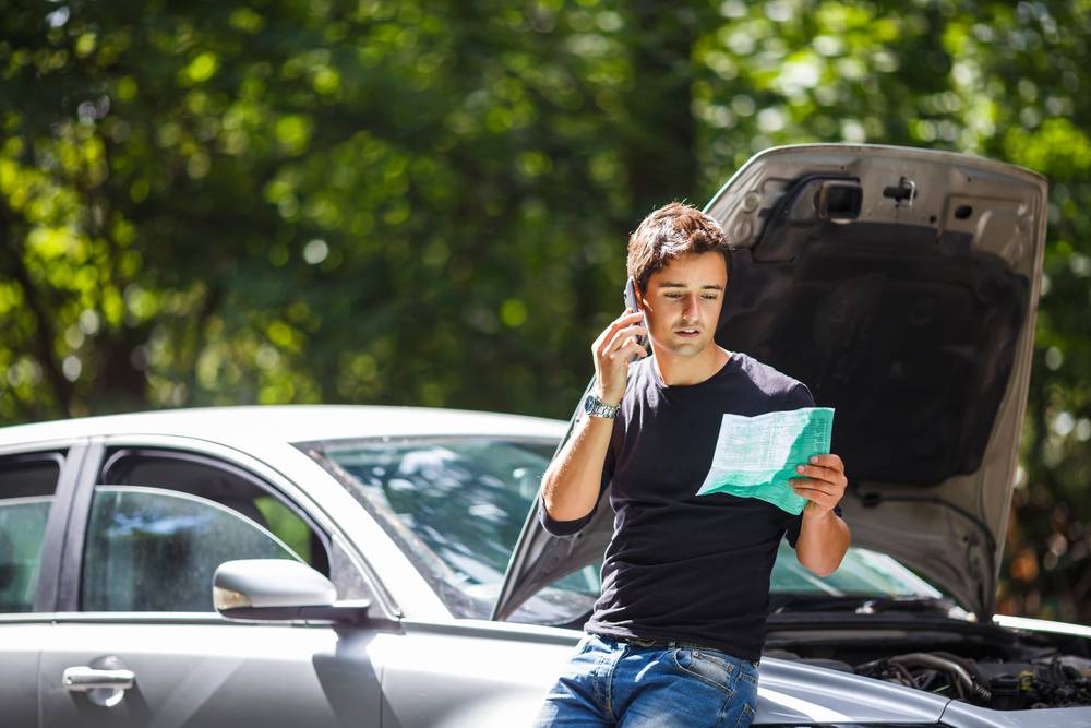 Photo of man next to the car with phone in hand