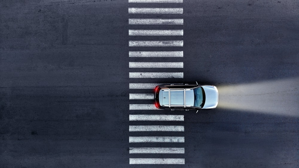 Shot from above of a car passing a pedestrian crosswalk