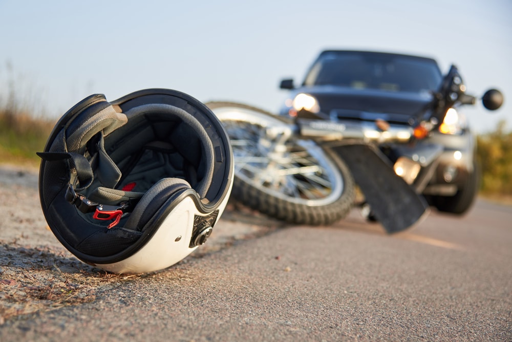 Closeup of helmet on road after a motorcycle crash with car in the background