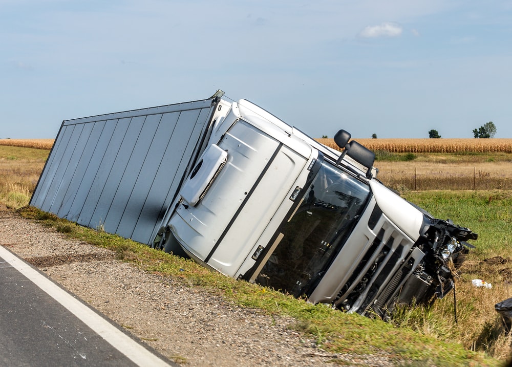 White semi-trailer truck tipped over in a ditch